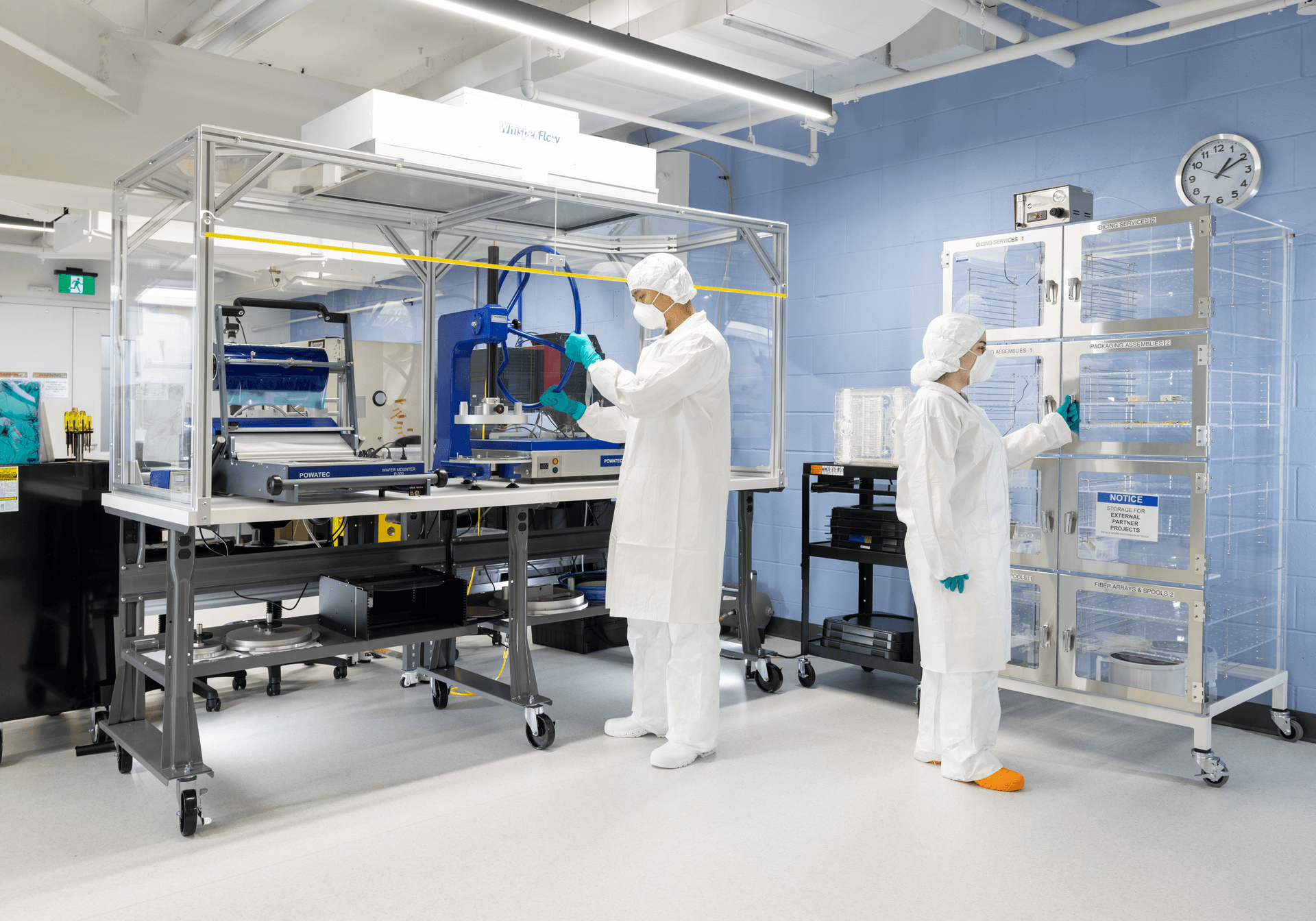 Two technicians in cleanroom suits working at the packaging line